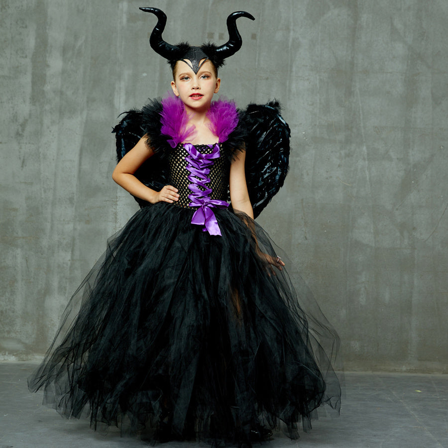 Child in a black and purple costume with horns and wings against a gray background