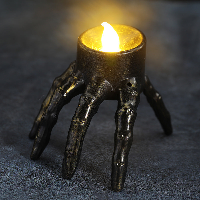 Candle holder shaped like a hand with a lit candle on a dark background