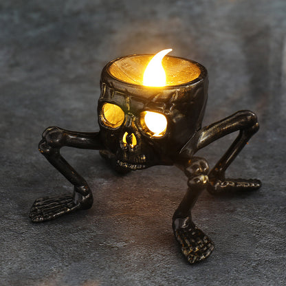 Skeleton-shaped candle holder with a lit candle on a dark surface