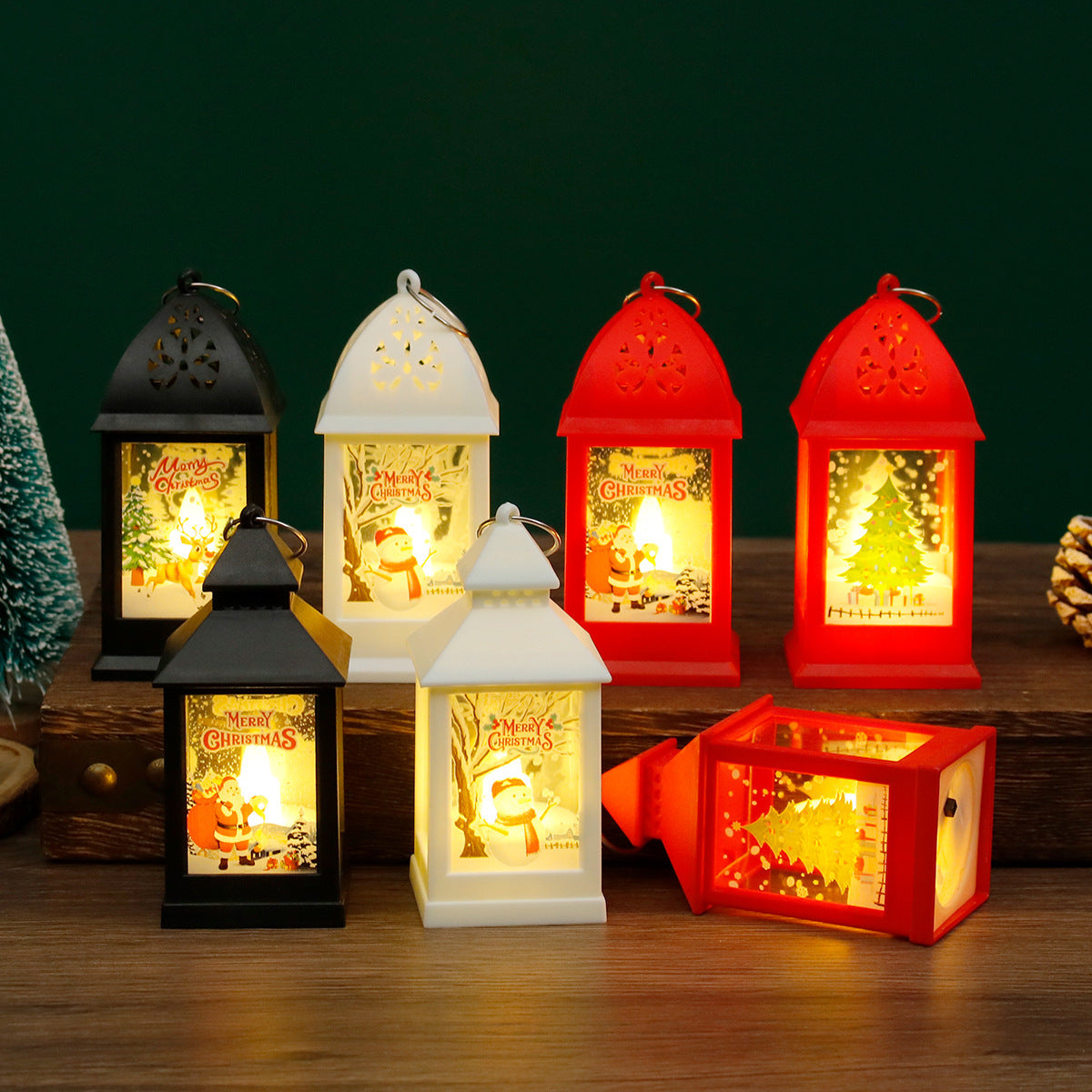 Set of colorful Christmas lanterns with glowing interior designs on a wooden surface.