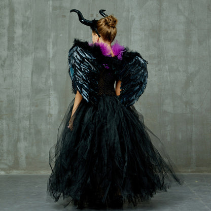 Person wearing a black, feathered costume with horns against a gray concrete wall.