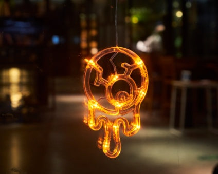 Decorative light fixture shaped like a jellyfish with glowing orange lights, blurred background