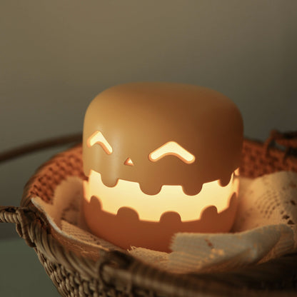 Ceramic jack-o'-lantern with a warm glow inside, placed in a woven basket on a soft background.
