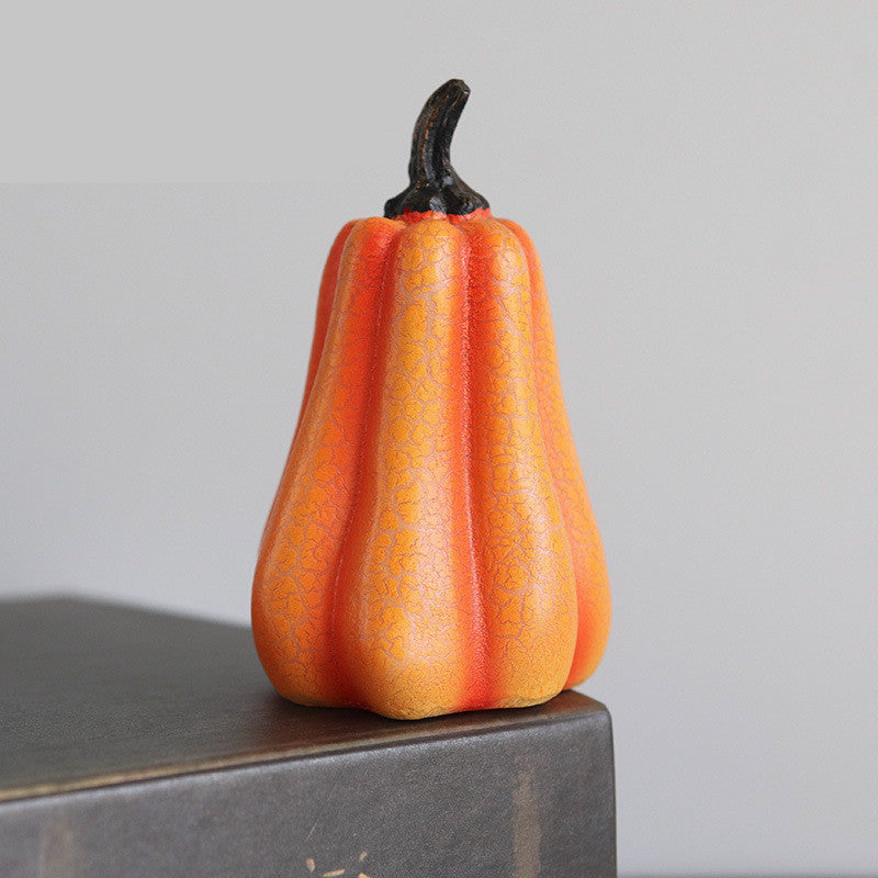 Decorative orange fruit with a black stem on a gray surface against a light gray background