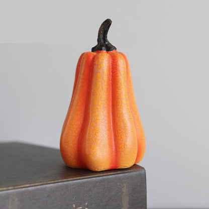 Decorative orange fruit with a black stem on a gray surface against a light gray background