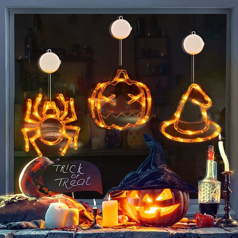 Halloween-themed decorations including a spider, pumpkin, witch hat, and lit jack-o'-lantern on a table.